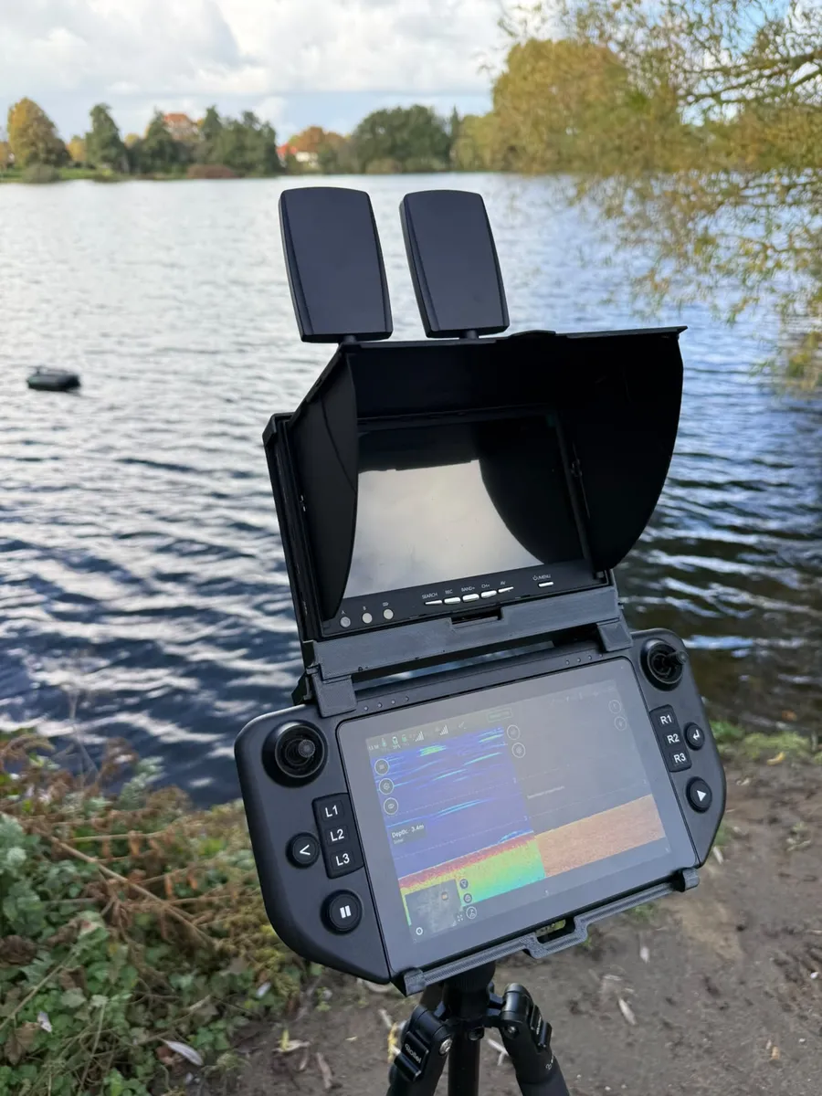 De Carplounge AIO-controller op een statief aan het meer, met de monitor van de Winchcam in de houder erboven en de voerboot op het water