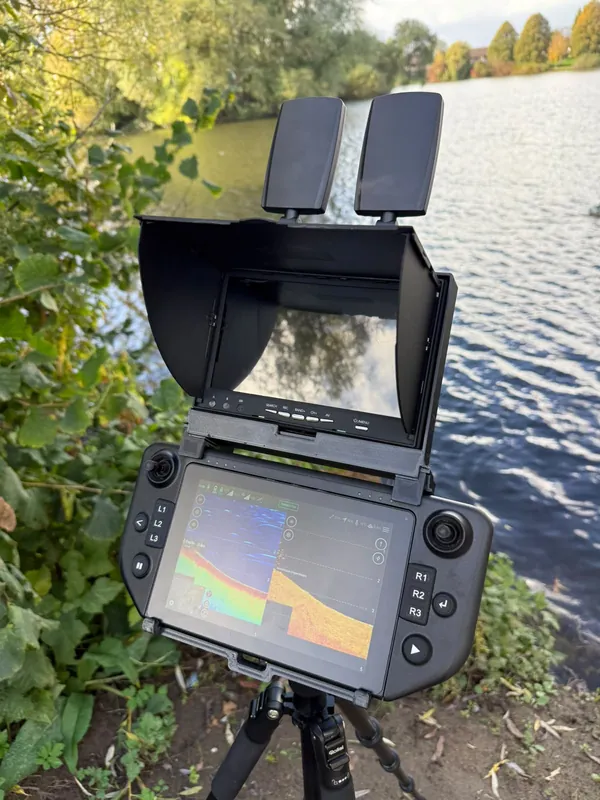 De Carplounge Winchcam-monitor met zonnekap in de houder, boven het sonarbeeld op de controller